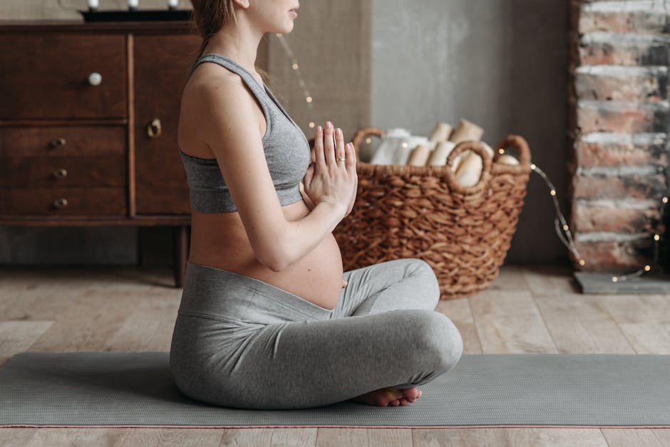 Woman in white activewear sitting calmly in a cross-legged yoga pose on a mat.
